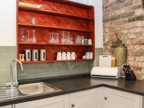 a kitchen with a sink and a shelf with glasses at Kilderkin in Bedale