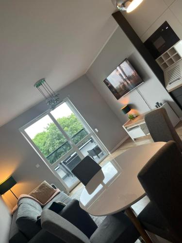 a living room with a table and chairs and a window at Apartament Nowoczesny w Centrum Torunia/podziemny parking i winda in Toruń