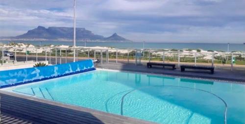 a large swimming pool with a view of the ocean at Cape Town Beachfront Accommodation in Blouberg in Bloubergstrand