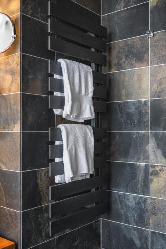 a towel rack in a bathroom with black tiles at b-smart hotel Menziken in Menziken