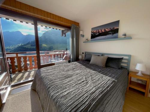 een slaapkamer met een bed en een balkon met uitzicht bij Grand-Bo: joli appartement sur les pistes avec vue in Le Grand-Bornand