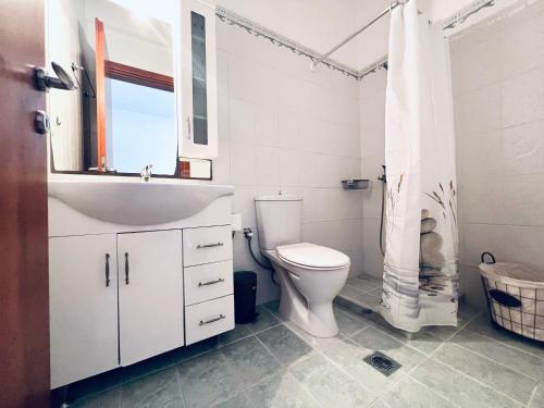 a white bathroom with a toilet and a sink at Four S Apartments in Mikonos