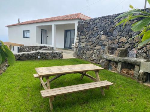 a wooden picnic table in front of a stone wall at LUZZ me - Casa das Doze Ribeiras in Doze Ribeiras