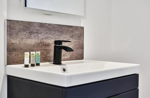 a bathroom sink with a black faucet and toothbrushes at Umry-Calm Farm Stays in Feeny