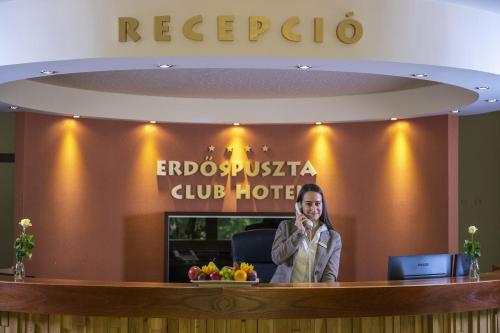 a woman sitting at a reception desk in a hotel at Erdőspuszta Club Hotel Fenyves in Debrecen
