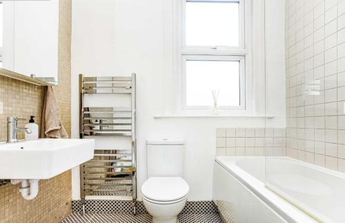 La salle de bains est pourvue de toilettes, d'un lavabo et d'une baignoire. dans l'établissement Bright and Stylish 2 Bedroom First Floor Flat, à Londres