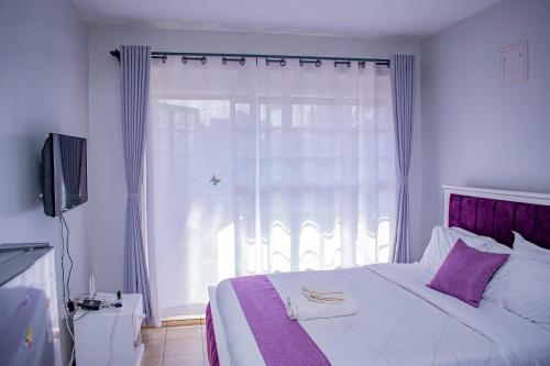 - une chambre avec un grand lit et une fenêtre dans l'établissement Belaire BnB Ruaka 3, à Ruaka