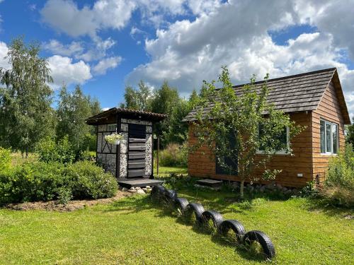 una pequeña cabaña en un patio con una fila de neumáticos en el césped en Kratikoda, en Rõõmu