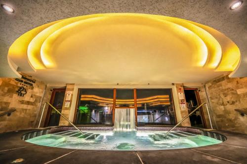 a swimming pool in a building with a yellow ceiling at Erdőspuszta Club Hotel Fenyves in Debrecen