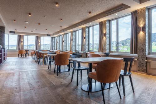 un restaurante con mesas, sillas y ventanas en b-smart hotel Menziken, en Menziken