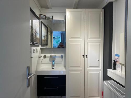 a white bathroom with a sink and a mirror at Beach Holiday Appartements in Dirkshorn