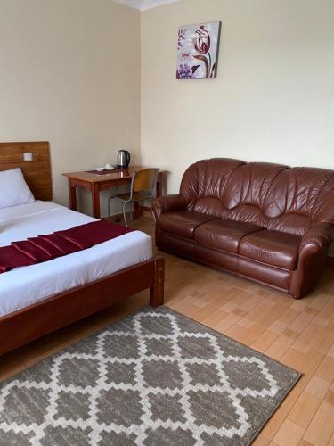 a bedroom with a bed and a leather couch at Acacia Gardens Gilgil in Gilgil