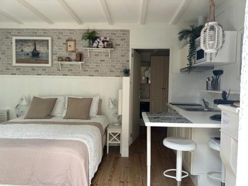 a bedroom with a bed and a desk and a kitchen at Beach Holiday Appartements in Dirkshorn
