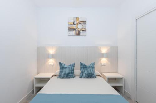 a bedroom with a large bed with blue pillows at Victoria's Apartamentos in Málaga