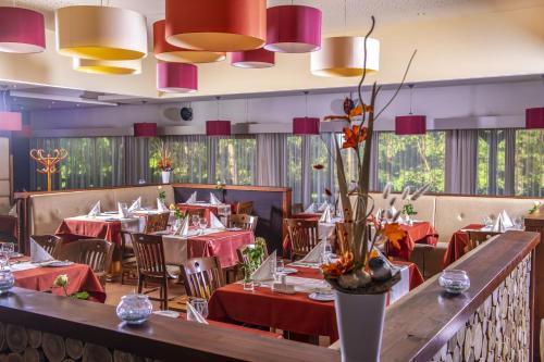 a dining room with red tables and chairs and pendant lights at Erdőspuszta Club Hotel Fenyves in Debrecen