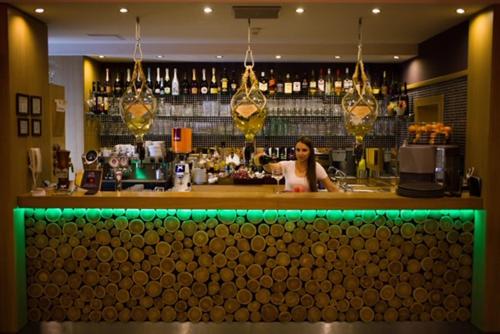 a woman standing behind a bar in a restaurant at Erdőspuszta Club Hotel Fenyves in Debrecen