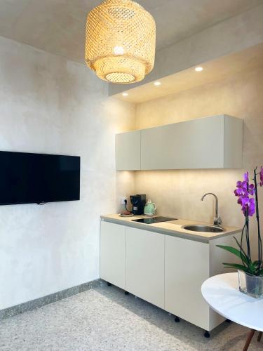 a kitchen with white cabinets and a flat screen tv at La casa di Irene - Suites con vista in Ragusa