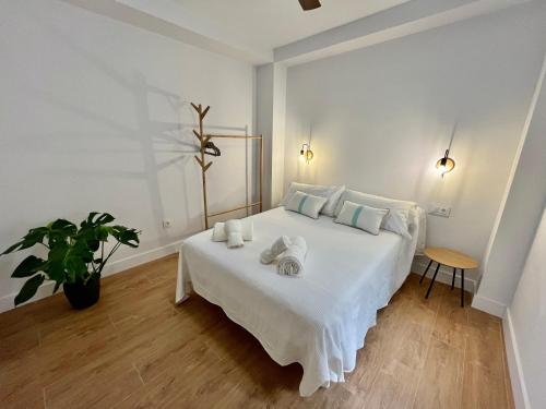 una camera da letto con un letto bianco con asciugamani sopra di Piso Picasso, Modern Apartment in the Heart of Malaga City a Málaga
