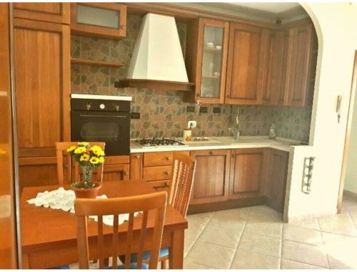 a kitchen with wooden cabinets and a table with flowers at Appartamento mare Torvaianica via Pola in Torvaianica