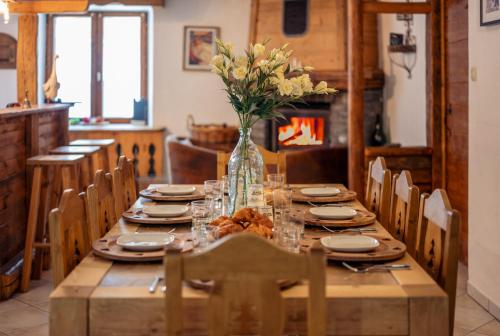 een houten tafel met een vaas met bloemen erop bij la maison des cerries in Hautecour
