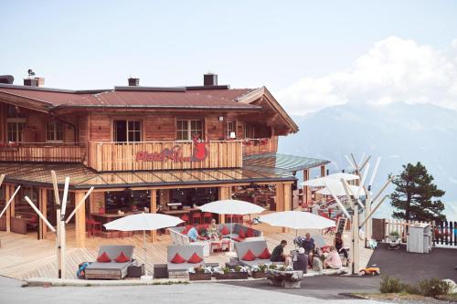 people sitting under umbrellas in front of a building at Berggasthof Platzlalm in Kaltenbach
