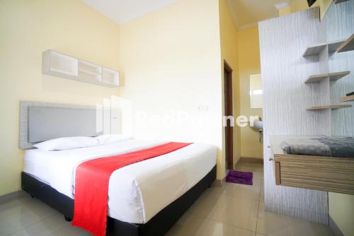 a bedroom with a large white bed with a red blanket at Indah Residence Syariah Mitra RedDoorz in Jakarta