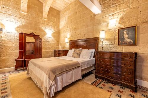 a bedroom with a bed and a dresser in it at Stunning Valletta Palazzino in Valletta
