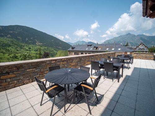 a patio with tables and chairs and a stone wall at Aparthotel Siente Boí & SPA in Pla de l'Ermita