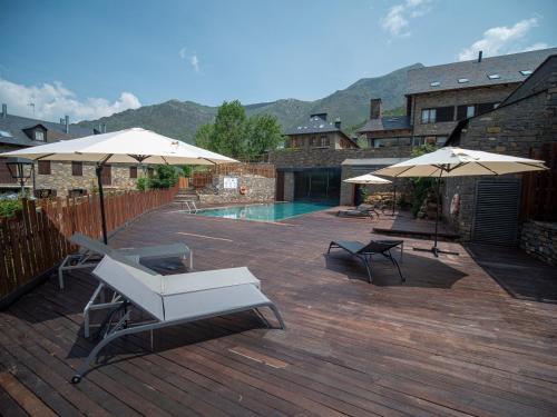 a deck with two umbrellas and a swimming pool at Aparthotel Siente Boí & SPA in Pla de l'Ermita