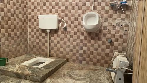 ein Badezimmer mit WC, Urinal und Waschbecken in der Unterkunft Parmarth Lok in Deoghar