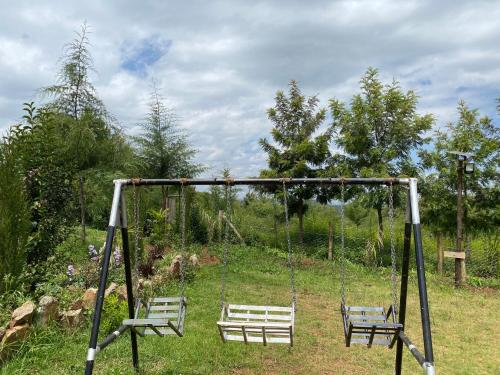 a swing set with two benches in a field at Acacia Gardens Gilgil in Gilgil