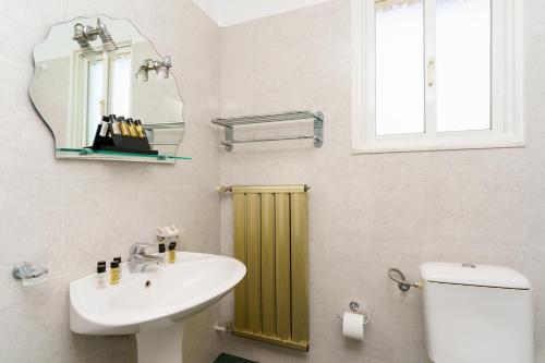 een badkamer met een wastafel, een toilet en een spiegel bij Stefania Hotel in Amarinthos