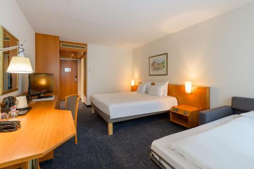 a hotel room with a bed and a desk at Novotel Freiburg am Konzerthaus in Freiburg im Breisgau