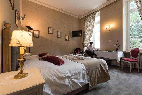 a hotel room with a bed and a person sitting in a chair at Logis La Résidence in Le Val-dʼAjol