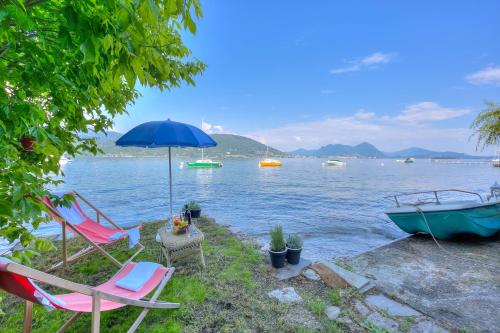 un par de sillas y una sombrilla junto al agua en Red House Terrace Private Beach - Happy Rentals, en Baveno