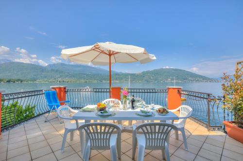 una mesa con sillas y una sombrilla en el balcón en Red House Terrace Private Beach - Happy Rentals, en Baveno