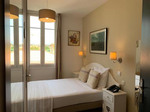 1 dormitorio con 1 cama con sábanas blancas y ventana en Hôtel La Villa des Oliviers, en Cagnes-sur-Mer