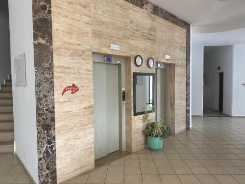 a lobby with two elevators and a wall with clocks at Appart-Hotel cabo negro in Cabo Negro