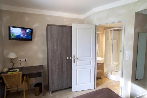 a room with a door and a desk and a television at Logis La Résidence in Le Val-dʼAjol