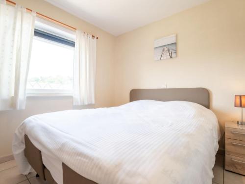 ein Schlafzimmer mit einem weißen Bett und einem Fenster in der Unterkunft Apartment Green Garden-8 by Interhome in De Haan