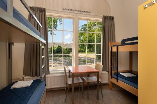 a bedroom with a table and a bed and a window at Stayokay Hostel Heemskerk in Heemskerk