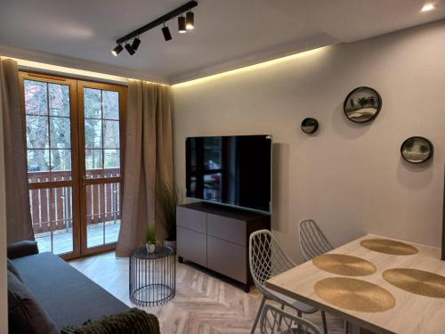 a living room with a tv and a table with chairs at Apartament Centrum - Szum potoku in Karpacz