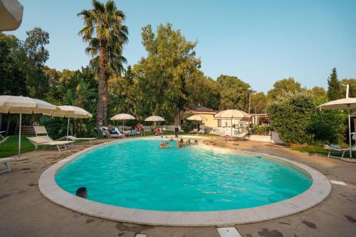 una piscina en un complejo con gente dentro en Kampaoh Flumendosa, en Santa Margherita di Pula
