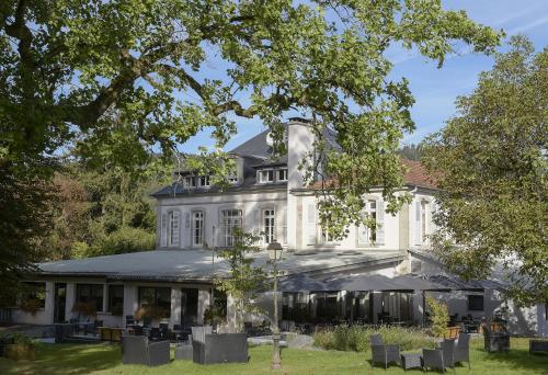 ein großes weißes Haus mit Stühlen im Hof in der Unterkunft Logis La Résidence in Le Val-dʼAjol
