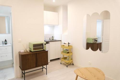 une cuisine avec une table et un four micro-ondes sur un comptoir dans l'établissement Le Contemporain - Studio en hypercentre - Toulouse, à Toulouse