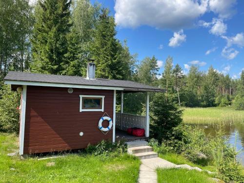 a small cabin with a porch next to a body of water at Saimaa Raikala in Vuoriniemi