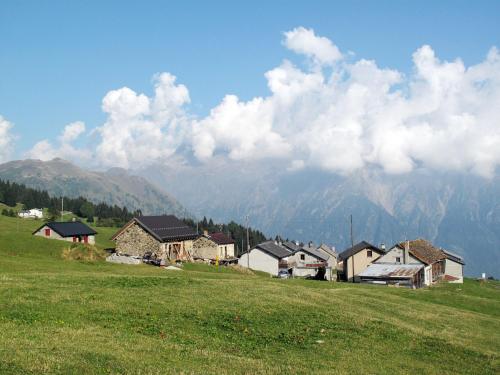 a group of houses on a hill with mountains in the background at Holiday Home Ca' Virc by Interhome in Olivone