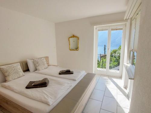 1 Schlafzimmer mit 2 Betten und einem großen Fenster in der Unterkunft Apartment Mulino Vecchio by Interhome in Ronco sopra Ascona