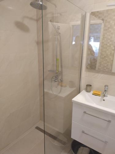 a white bathroom with a shower and a sink at Apartments Miličević in Gradac