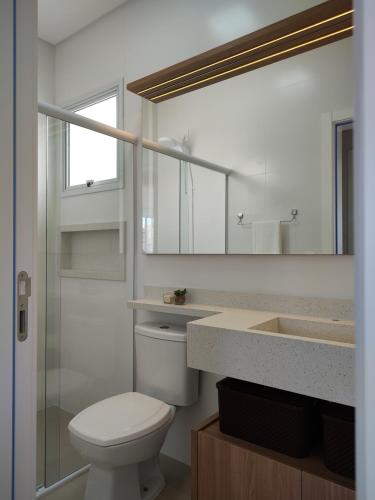 a bathroom with a toilet and a sink and a mirror at Praia de Palmas - Lindo Apartamento in Governador Celso Ramos